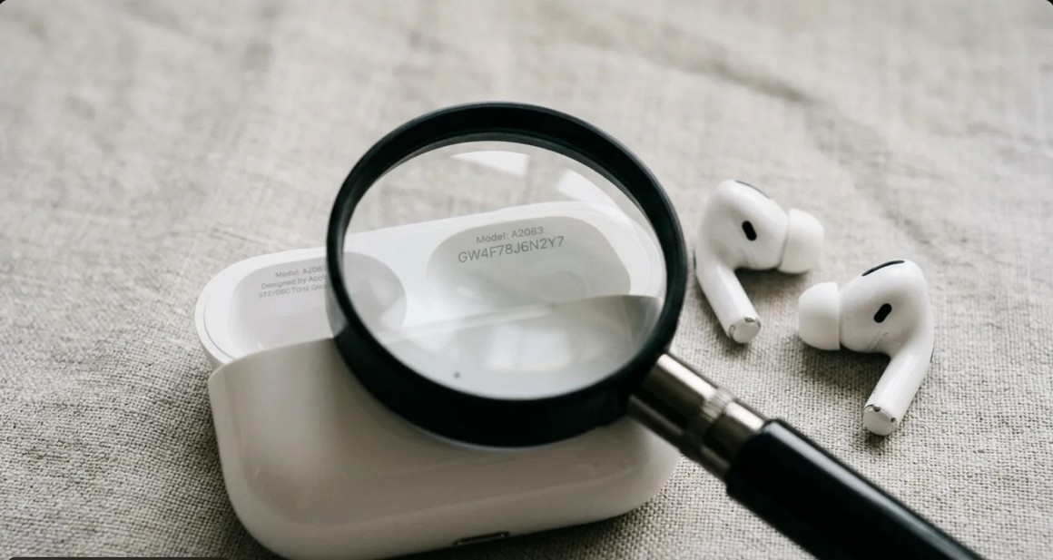 Лупа над открытым кейсом AirPods с серийным номером под крышкой